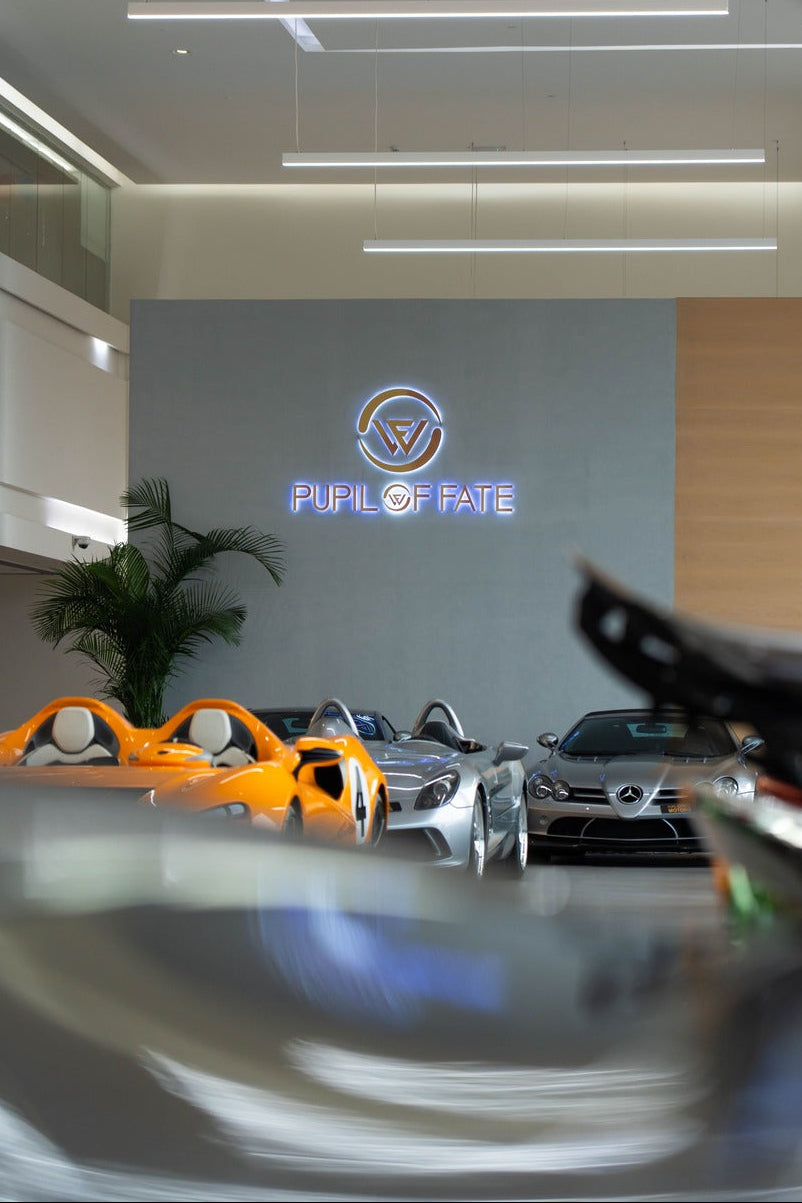 Car showroom with multiple cars on display and a logo on the wall.